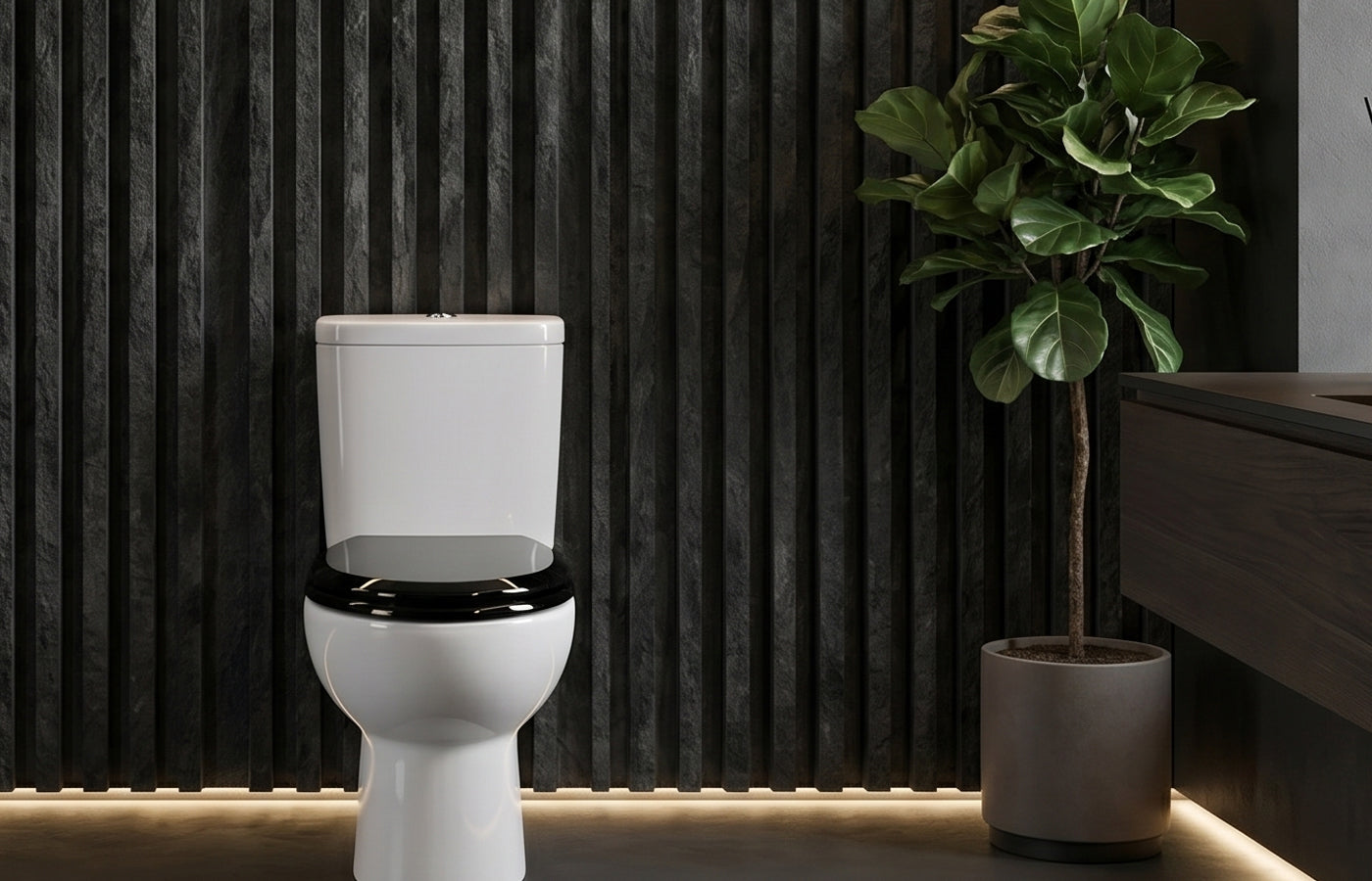 TOPSEAT PRO ELITE series black toilet seat with a high-gloss finish, shown on a white ceramic toilet in a moody luxury bathroom. The background features dark charcoal fluted stone walls, an indoor Fiddle Leaf Fig plant, and warm ambient LED floor lighting, emphasizing the mirror-like reflective surface of the black seat cover.